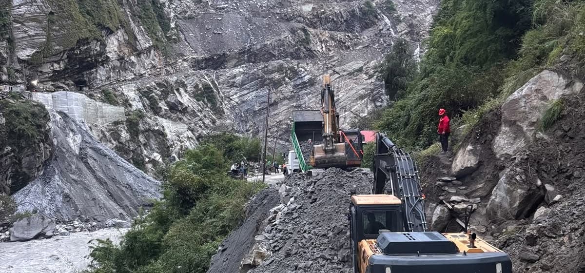 Excavators and a dump truck remove rocks and landslide debris on a mountain cliff road.
