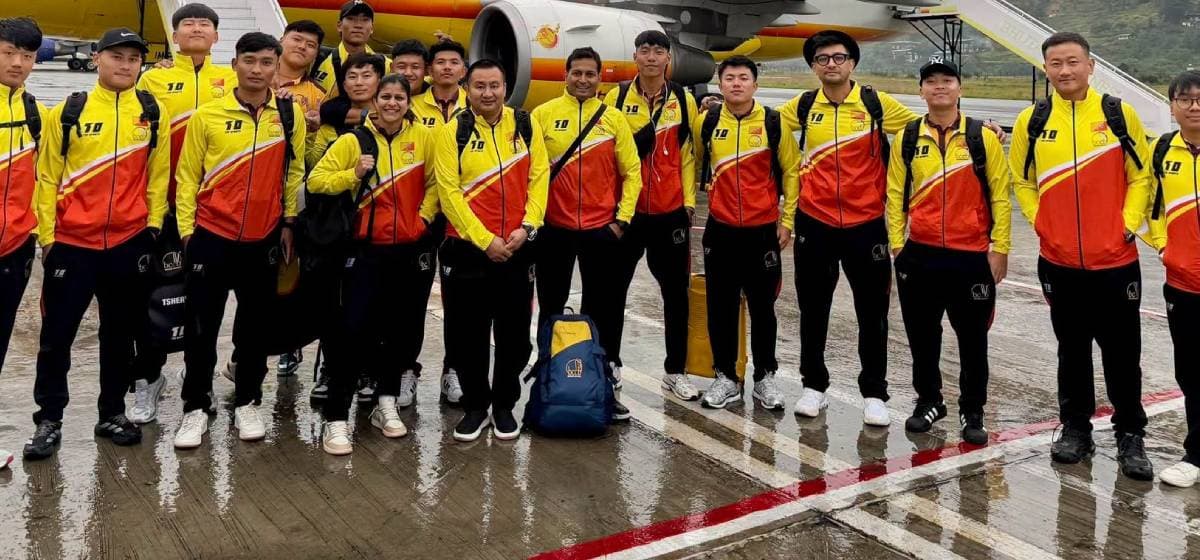 Members of the Bhutan men's national cricket team pose on an airport tarmac.