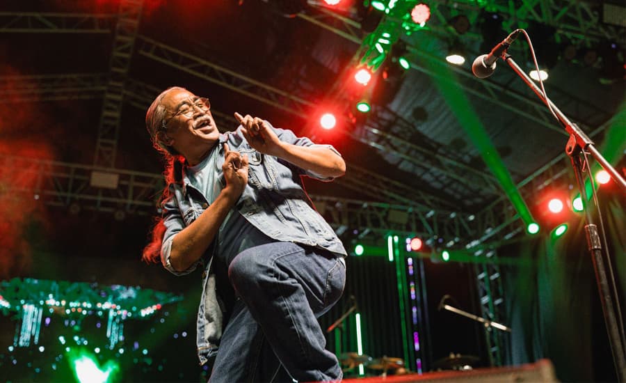Nepathya frontman Amrit Gurung dances and sings on stage under concert lights.
