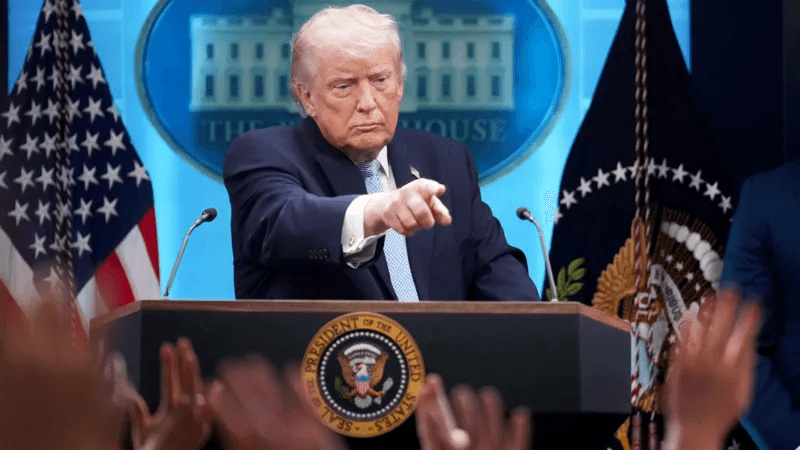 Donald Trump points toward reporters from behind the White House press podium.