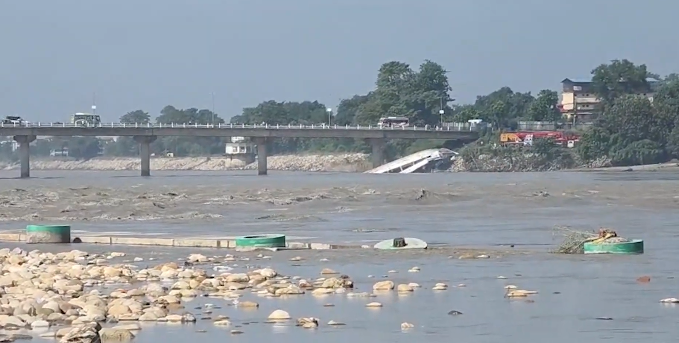 The flooded Narayani River flowing near a concrete bridge with submerged banks.