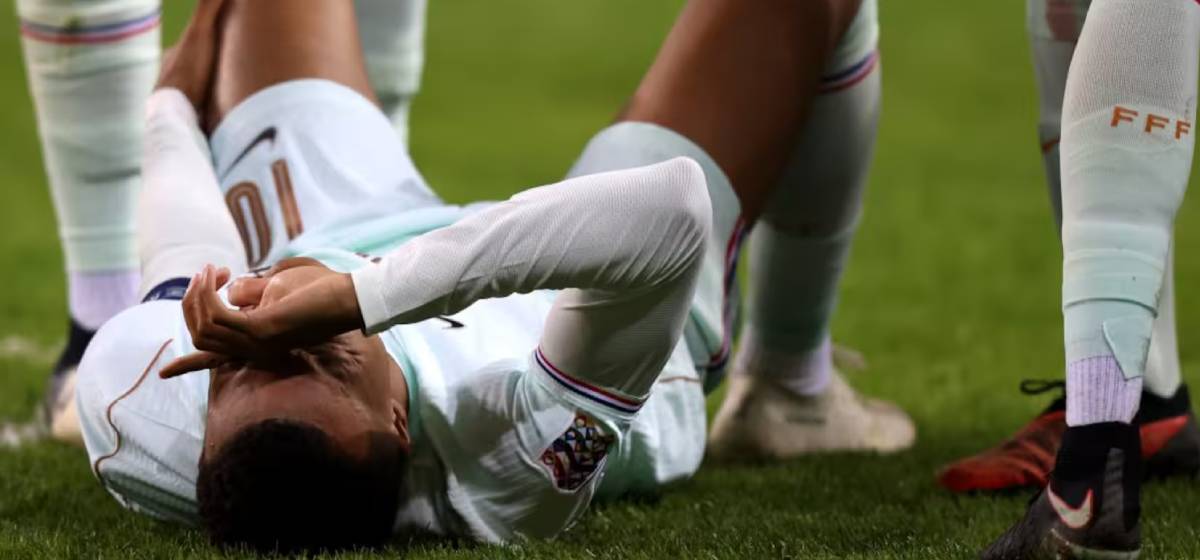 Kylian Mbappé lying on the pitch in pain after injuring his knee during France's match.