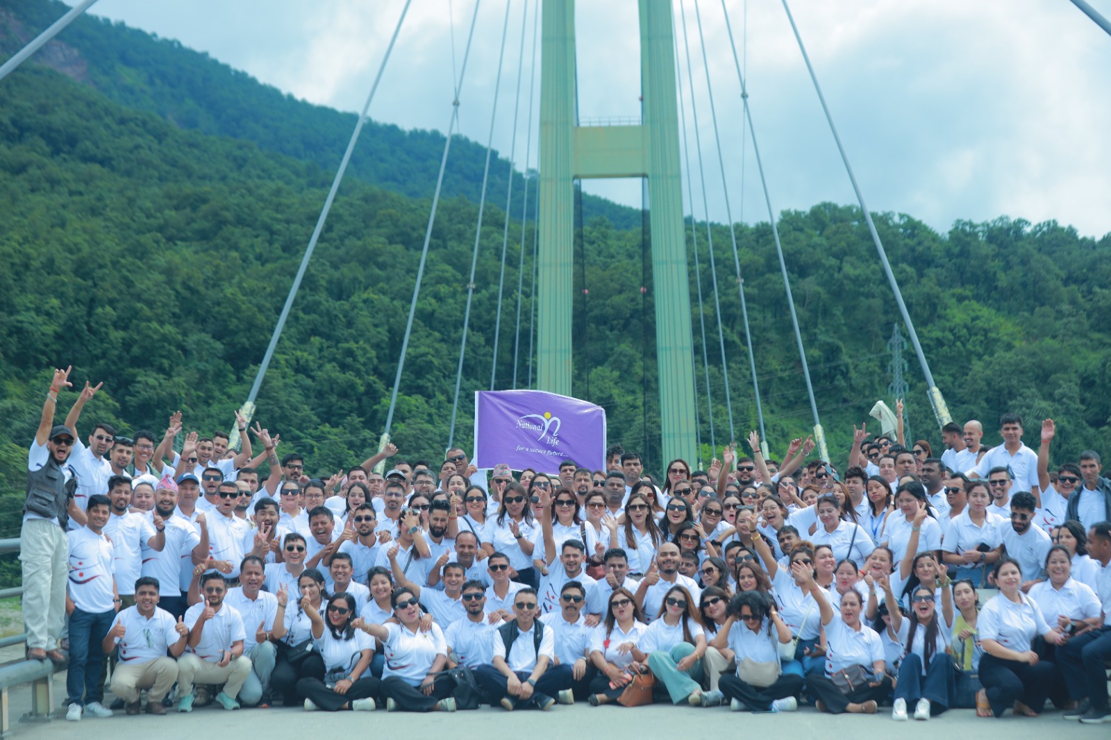 National Life Insurance employees posing with a company flag on the Karnali Bridge at Chisapani.