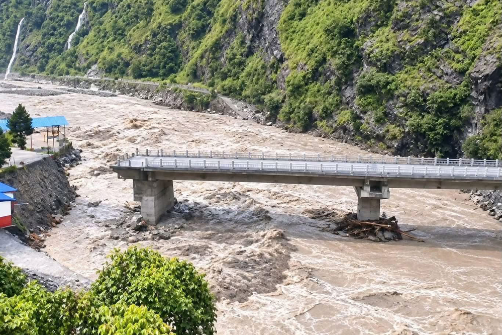 A concrete bridge over a swollen river with eroded access roads along the transit corridor.